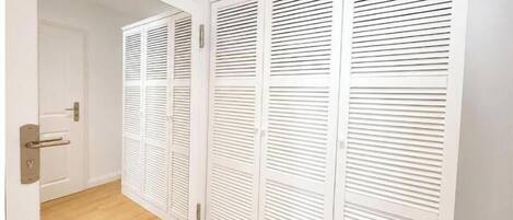 Un armario blanco con puertas correderas y piso de madera.
