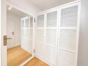 A white closet with sliding doors and a wooden floor. - Sea Studio - Modern time-out right on the beach in Scharbeutz (Scharbeutz)