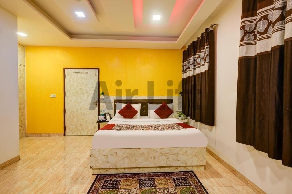 A hotel room with a bed, a nightstand, a mirror, a door, and a patterned rug.