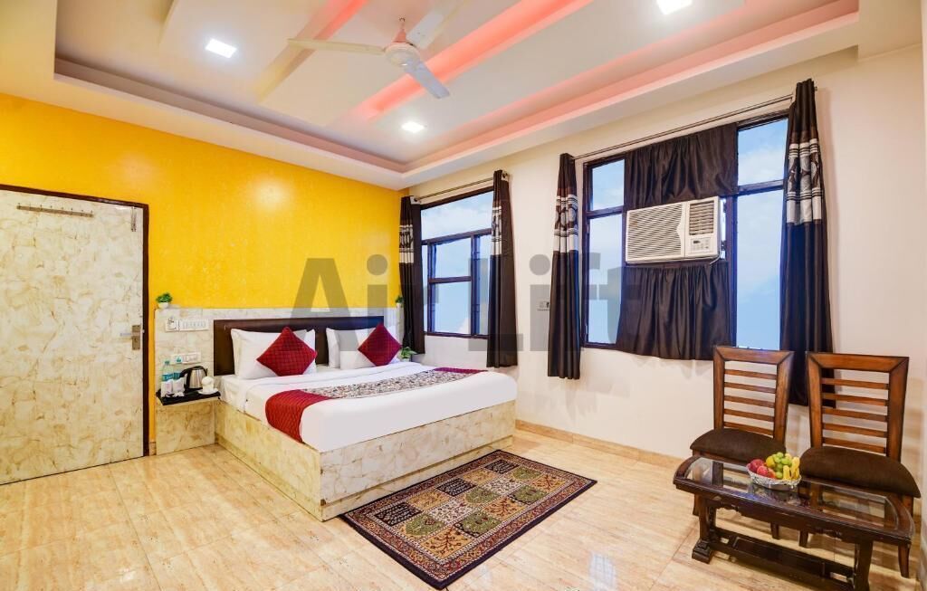 A bedroom with a bed, a nightstand, a chair, a window with curtains, and an air conditioning unit.