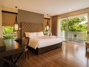 Habitación de hotel con una cama grande, un escritorio y un balcón con mobiliario exterior.