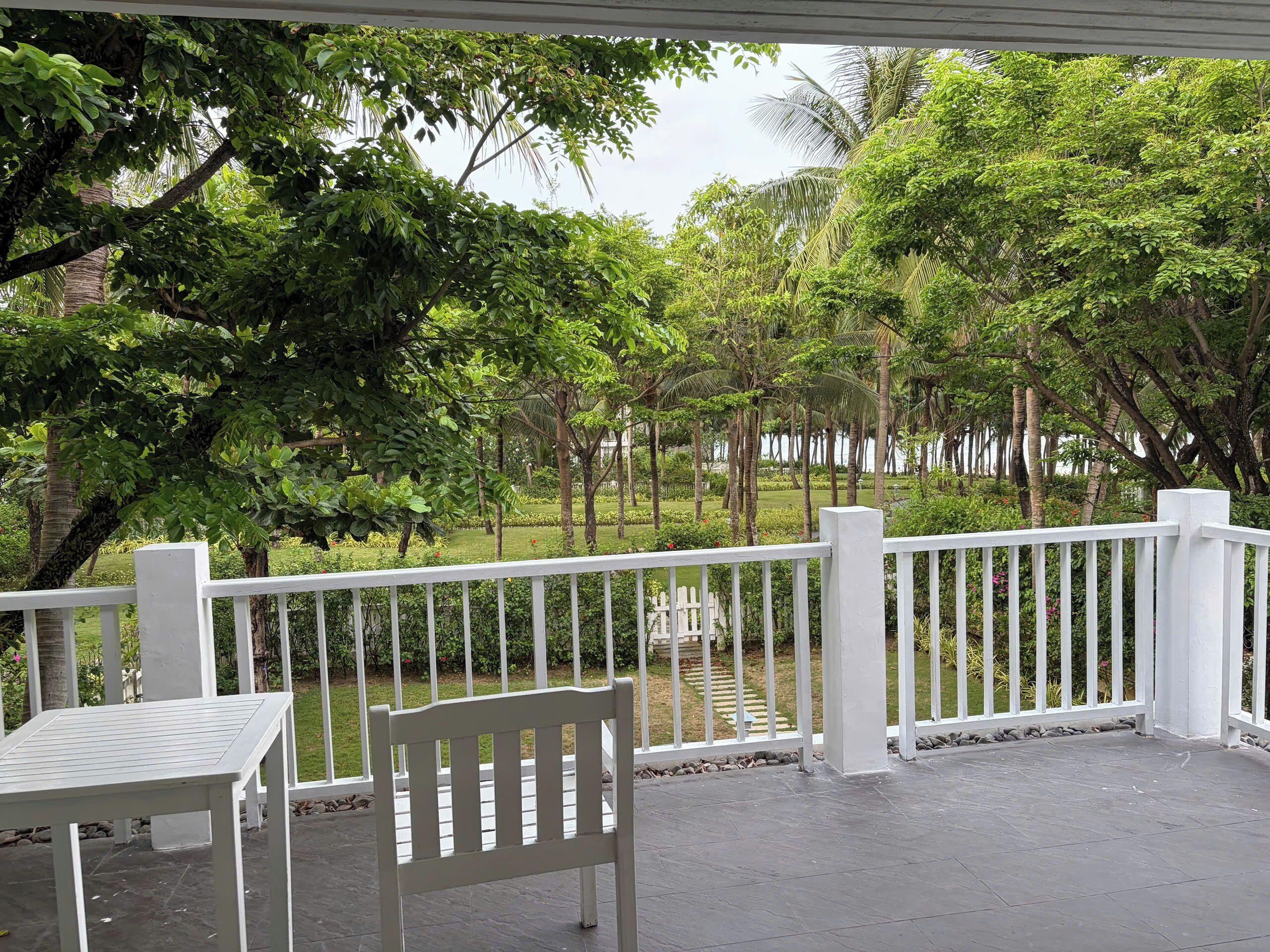 A covered outdoor area with a white railing, a bench, and a table.