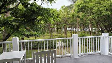 A covered outdoor area with a white railing, a bench, and a table.