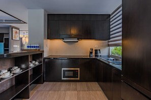 Una cocina moderna con gabinetes oscuros, horno empotrado y ventana con vistas al verdor.