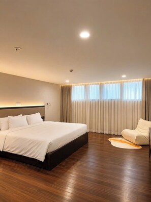 Una habitación de hotel moderna con una cama grande, un área de descanso y vista al cielo a través de la ventana.