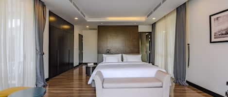 Une chambre d’hôtel moderne avec un grand lit, un canapé, une petite table et une chaise.