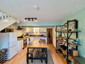 A modern kitchen with white cabinets, a wooden dining table, and a built-in oven. - Cosy 2bed house in Reading (Reading)