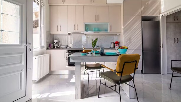 Eine moderne Küche mit weißen Schränken, einem Edelstahl-Kühlschrank und einem Essbereich mit Tisch und Stühlen.