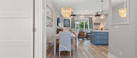 Una cocina moderna con encimera azul, un comedor con sillas de mimbre y un ventilador de techo.