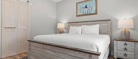 A bedroom with a wooden bed, two bedside tables with lamps, a large window, and a sliding door.
