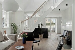 Ein modernes Interieur mit Treppe, Essbereich und Sitzecke mit Kamin.