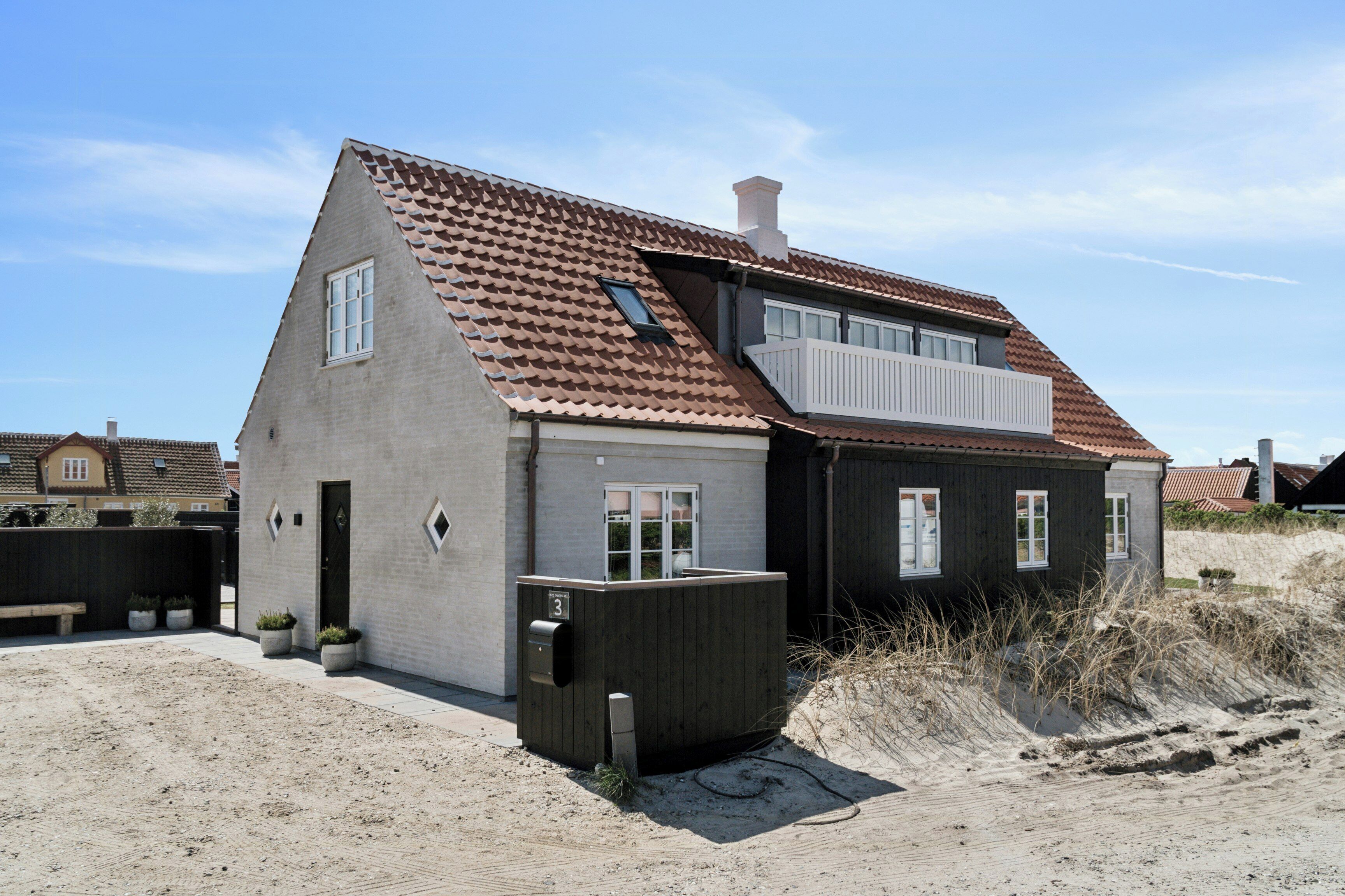 A two-story house with a sloped roof, a small balcony, and a wooden fence.