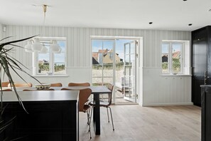 Eine moderne Küche mit Essbereich, großen Fenstern und Blick ins Freie.