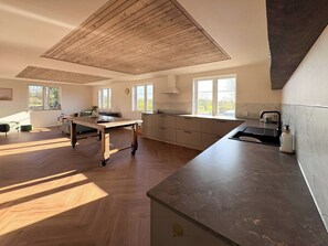 Una cocina espaciosa con piso de madera, una isla grande y vistas al exterior.