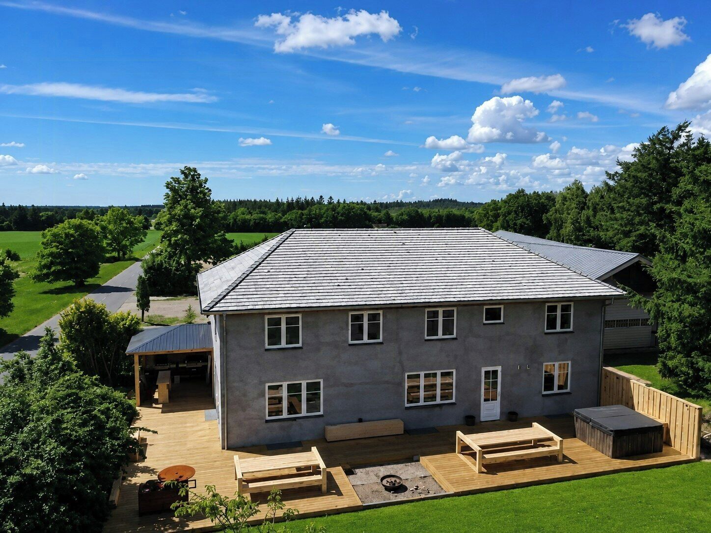A two-story house with a patio, a hot tub, and a covered outdoor seating area.