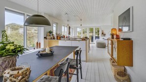 Een moderne keuken met een groot schiereiland, een eethoek en uitzicht op het omliggende landschap.