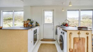 Een kleine keuken met een centrale deur, een wasmachine en een gootsteen.