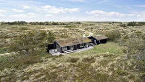Een modern huis met een ruim terras, omgeven door een natuurlijke omgeving.