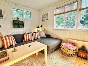 Ein gemütliches Zimmer mit einer Couch, einem kleinen Tisch, einer Lampe, einem Korbwäscher und einem Laternen.