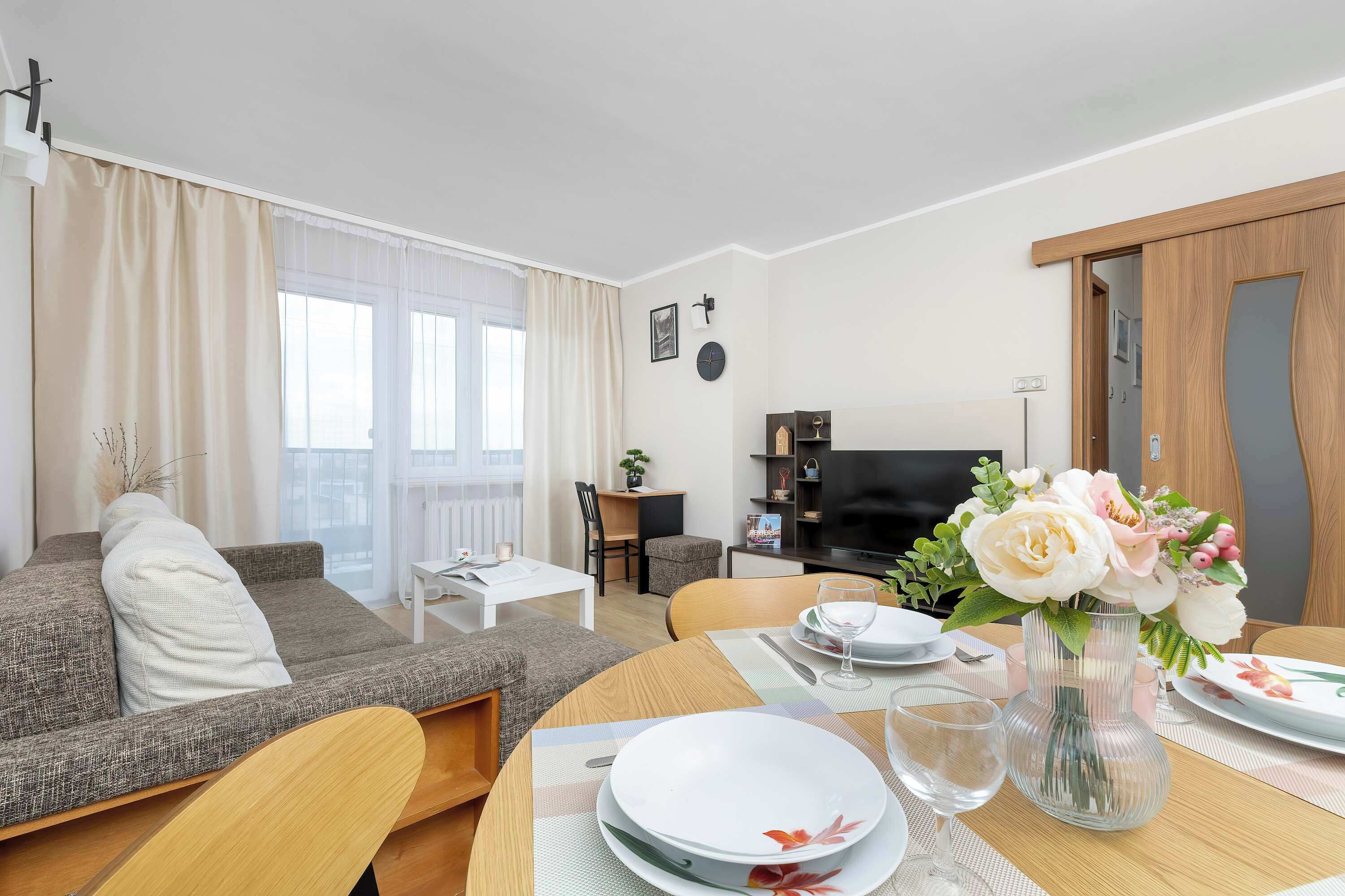 A modern living room with a sofa, dining table, and a TV.