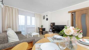 A modern living room with a sofa, dining table, and a TV.