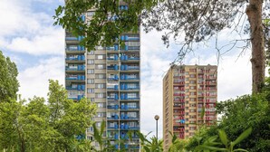 Un edificio residenziale alto con balconi, circondato da vegetazione e alberi.