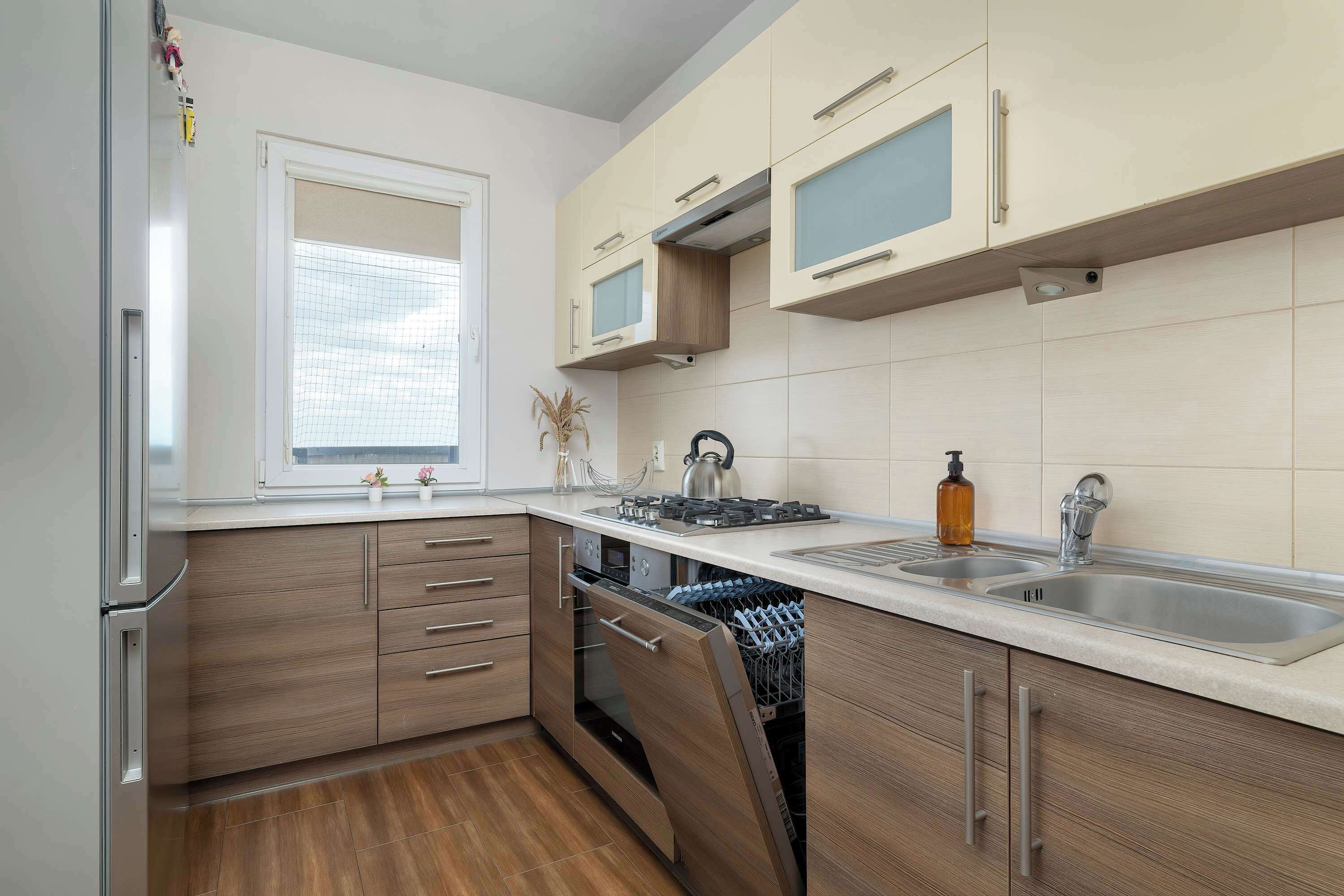 A modern kitchen with built-in appliances, a dishwasher, and a window.