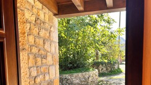 Un mur de pierre, une porte en bois et un espace extérieur pavé agrémenté d’arbres.