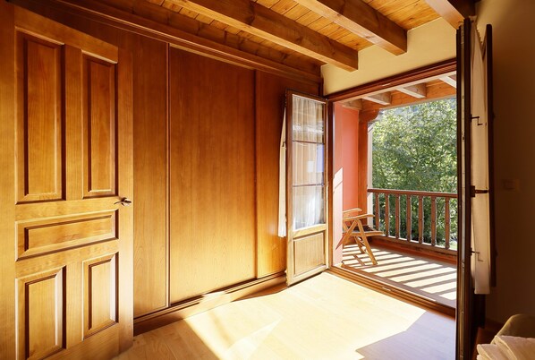 Ein Zimmer mit Holzwänden, einer Schiebetür zu einem Balkon mit Holzgeländer und einem Holzboden.