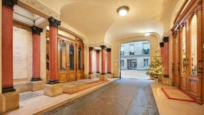 Un amplio pasillo con pisos de mármol, columnas de madera y un árbol de Navidad.