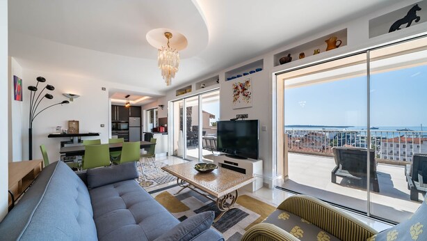 Una sala de estar moderna con un sofá, un televisor y un balcón con vistas.