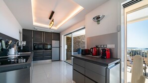 Una cocina moderna con una isla grande, electrodomésticos integrados y vistas al exterior.