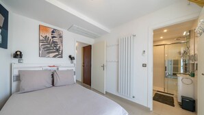 Un dormitorio con cama, puerta que da a un baño y zona de ducha.
