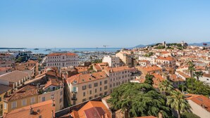 Un paisaje urbano costero con edificios históricos, un puerto deportivo y una torre destacada.