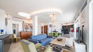 Una sala de estar moderna con un sofá, sillas, una mesa de comedor y una cocina al fondo.