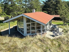 A modern house with a glass extension, a deck, and outdoor seating. - House with wide views in dunes near Blokhus (Blokhus)