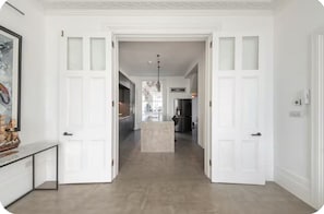 A hallway with white doors, a kitchen area with a refrigerator, and a pendant light. - 3 bedroom, 3 bathroom ocean view with padel boards (Hastings)