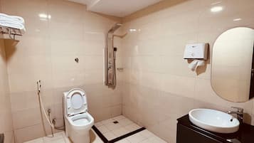 A modern bathroom with a toilet, shower, sink, and a towel rack.