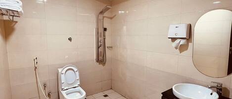A modern bathroom with a toilet, shower, sink, and a towel rack.