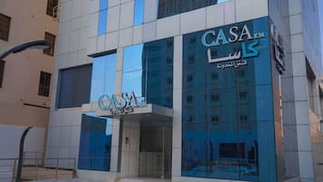A modern building with the sign 'CASA' prominently displayed, featuring a reflective glass facade and a tiled entrance area.