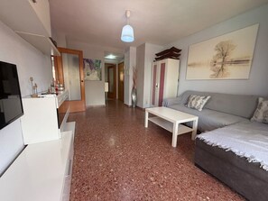 Ein Wohnzimmer mit einer Couch, einem Couchtisch, einem Fernseher und einem Bild an der Wand.