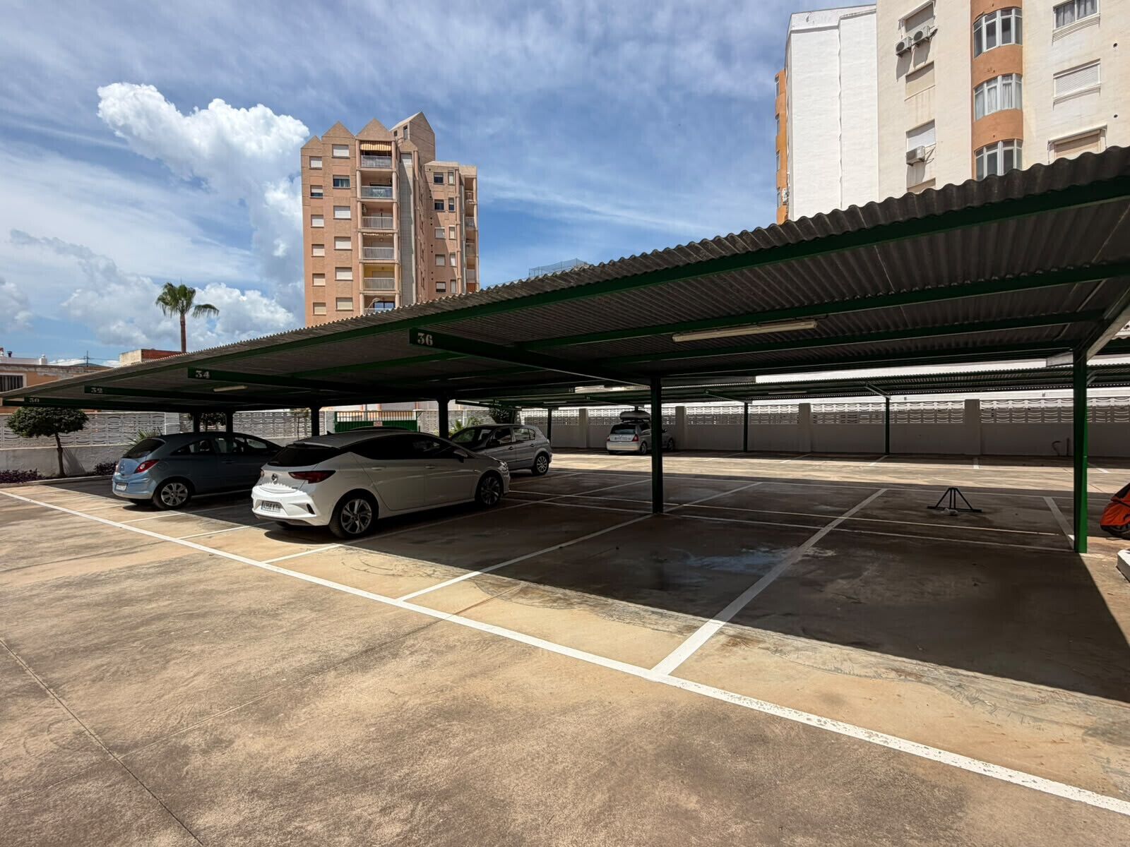 A parking garage with multiple levels, a covered area, and a tall building in the background.