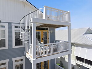 Ein zweistöckiges Gebäude mit einem Balkon, einer Glastür und einem Fenster mit weißem Rahmen.