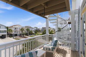 A balcony with a white railing, a chair, and a small table. - Coastal Villa #208, Carolina Beach, Easy Beach Access, Remodeled (Carolina Beach)