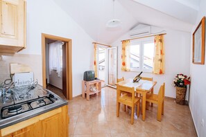 Una cucina con piano cottura a gas, mobili in legno, un tavolo da pranzo con sedie e un televisore su un piccolo mobile.
