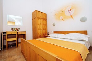 Ein Schlafzimmer mit Bett, Holzschrank, Schreibtisch und Spiegel.