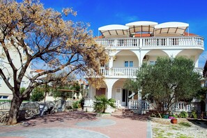 Un edificio a più piani con balconi, un cortile con una palma e un muro in pietra.