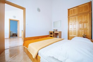 Una camera da letto con un letto, un'armadio in legno, una scrivania e uno specchio.