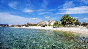A coastal area with clear water, a sandy beach, and buildings with red roofs. - Moretti Stay Near Vodice Center (Vodice)