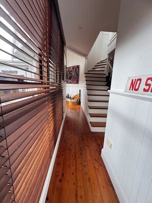 A hallway with wooden blinds, a staircase, and a 'NO STEP' sign.
